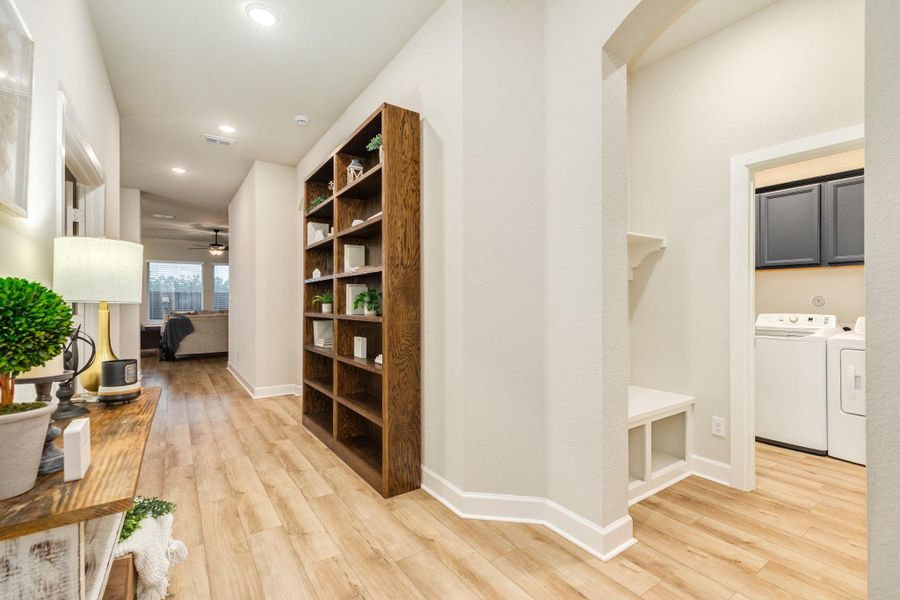 This view shows the laundry room and mud room area. The laundry room has built-in navy blue cabinets, beige shelving, and white-topped appliances, which can stay with the home.