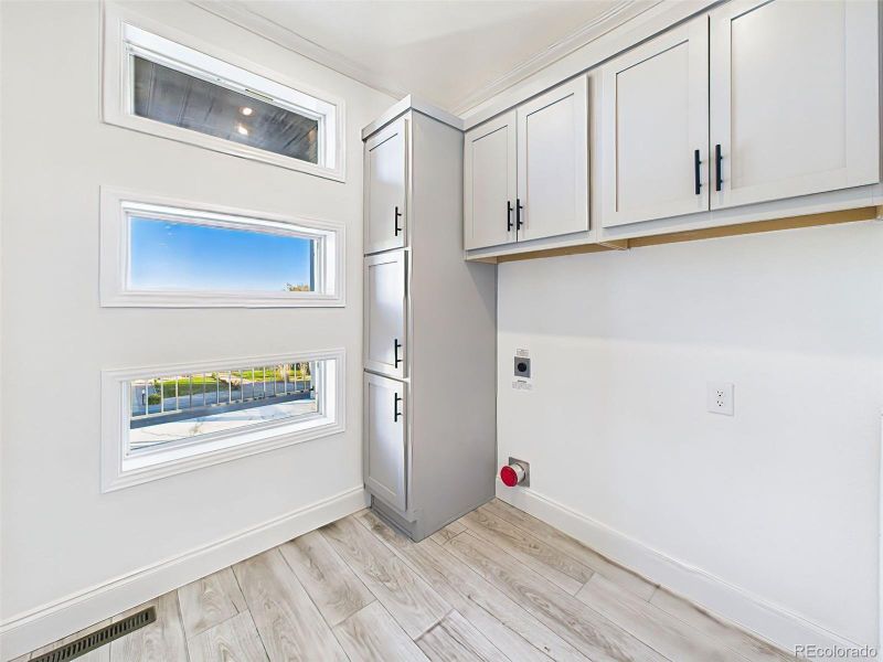 Dedicated laundry space with custom cabinetry, and unique window detail adding natural light. Dedicated laundry space with custom cabinetry, and unique window detail adding natural light.