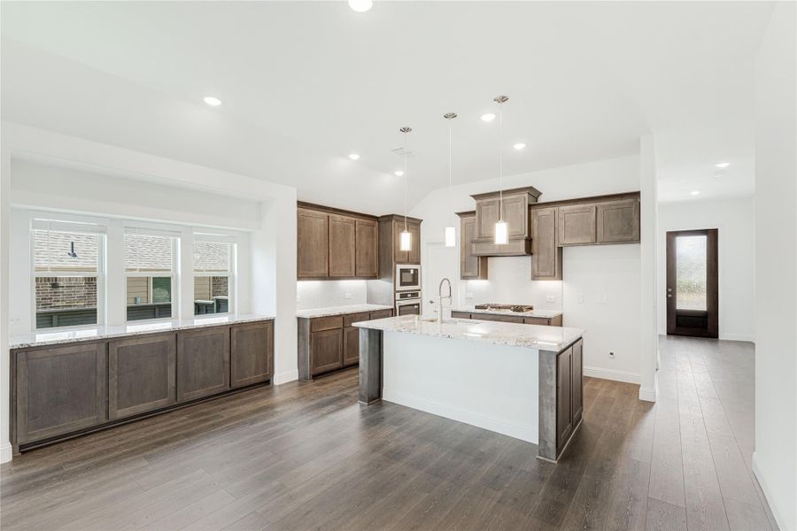 Kitchen with dark wood cabinets, center island with granite countertops, and hardwood floors Kitchen with dark wood cabinets, center island with granite countertops, and hardwood floors