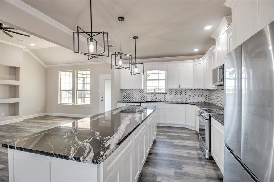 Kitchen featuring stainless steel appliances, dark wood-type flooring, a center island, open floor plan, and dark stone counters