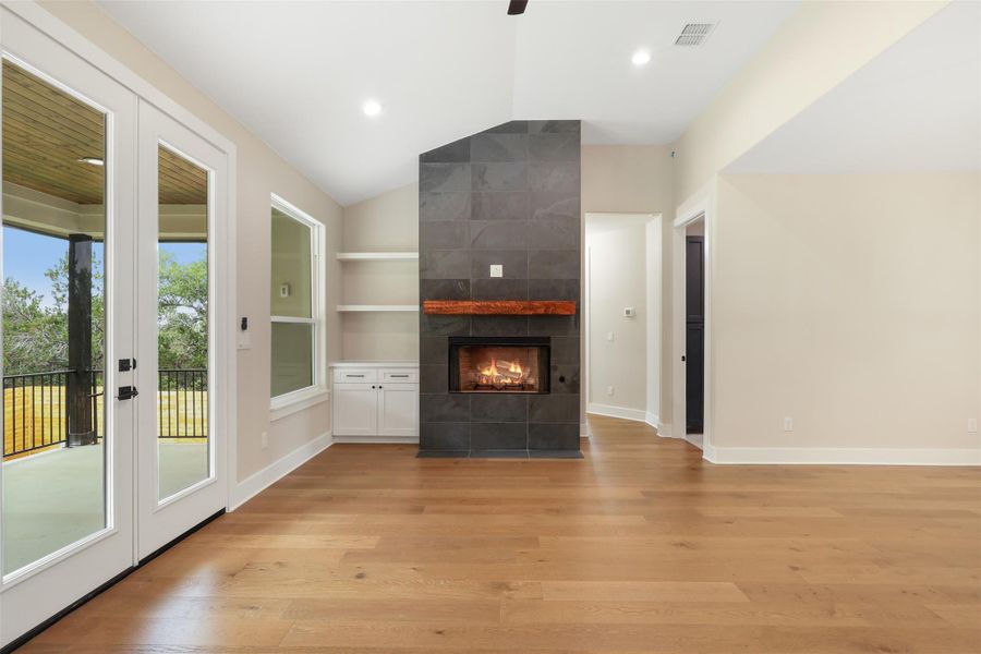 Unfurnished living room with light wood-type flooring, plenty of natural light, and vaulted ceiling Unfurnished living room with light wood-type flooring, plenty of natural light, and vaulted ceiling