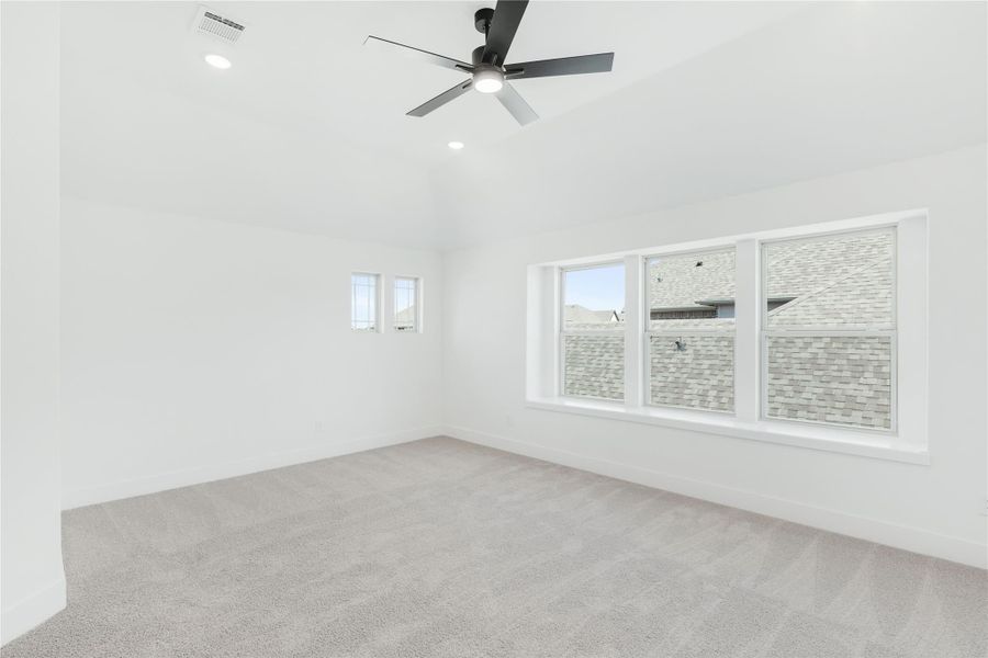 Empty bedroom with gray carpet, ceiling fan, and large windows with neighborhood view