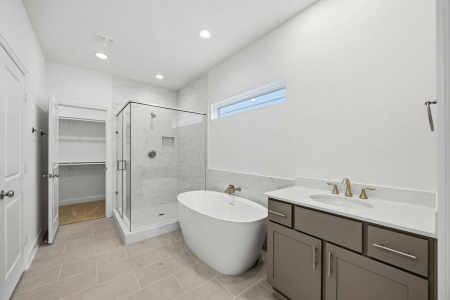 Spa-Like Retreat. The luxurious primary bath features a freestanding tub, a walk-in shower, and designer tile for a relaxing escape.