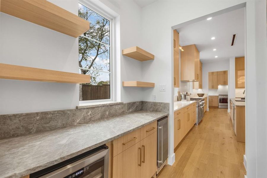 Kitchen with light brown cabinets, open shelves, light stone countertops, wine cooler, and light wood finished floors