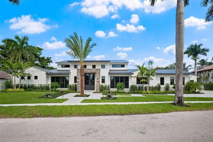 Contemporary residence featuring a clean-lined facade, multi-level roofline with metal roofing, stone veneer accent at the entryway, and expansive windows Contemporary residence featuring a clean-lined facade, multi-level roofline with metal roofing, stone veneer accent at the entryway, and expansive windows