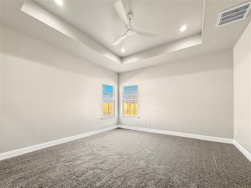Empty room with carpet, ceiling fan, recessed lighting, and a tray ceiling Empty room with carpet, ceiling fan, recessed lighting, and a tray ceiling