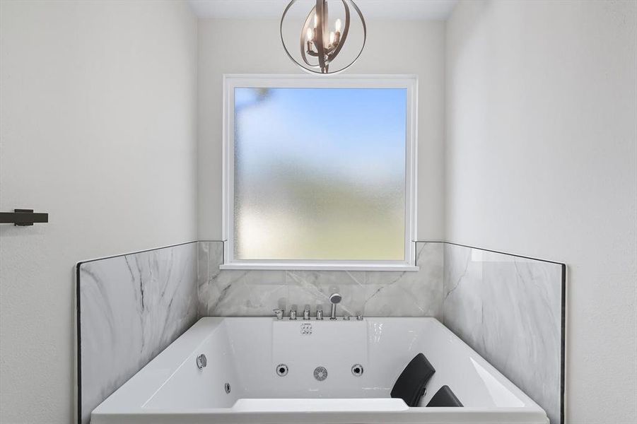 Bathroom featuring a tub with jets and a chandelier Bathroom featuring a tub with jets and a chandelier