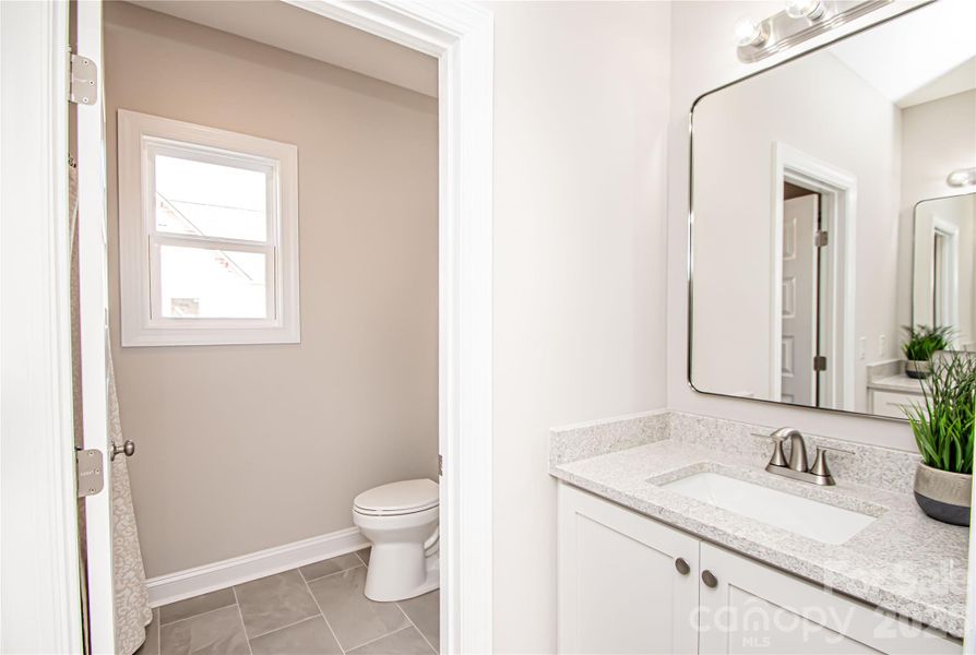 The hall bathroom boasts tile floors, dual white vanities, an oversized mirror, and brushed nickel fixtures and hardware for a clean, modern look.