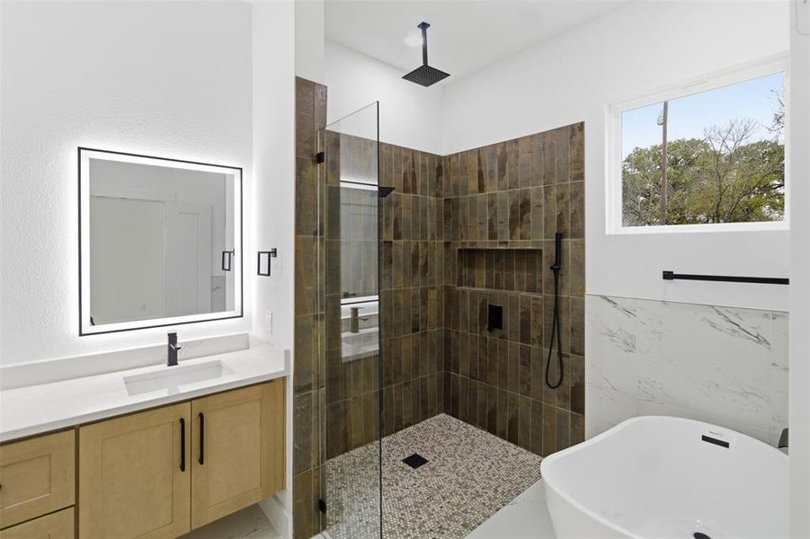 Bathroom with a freestanding bath, a walk in shower, and vanity