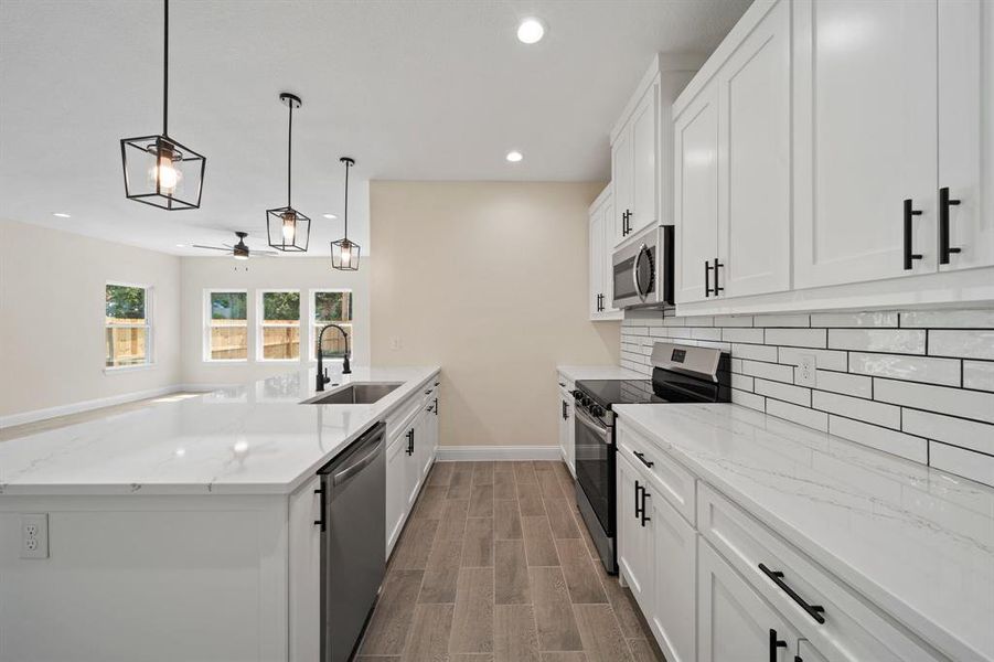 Kitchen featuring dark hardwood / wood-style floors, ceiling fan, appliances with stainless steel finishes, white cabinets, and sink