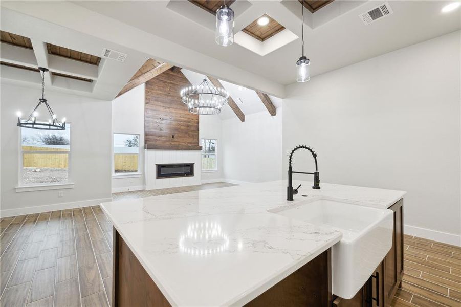 Kitchen with sink, a kitchen island with sink, pendant lighting, and a fireplace