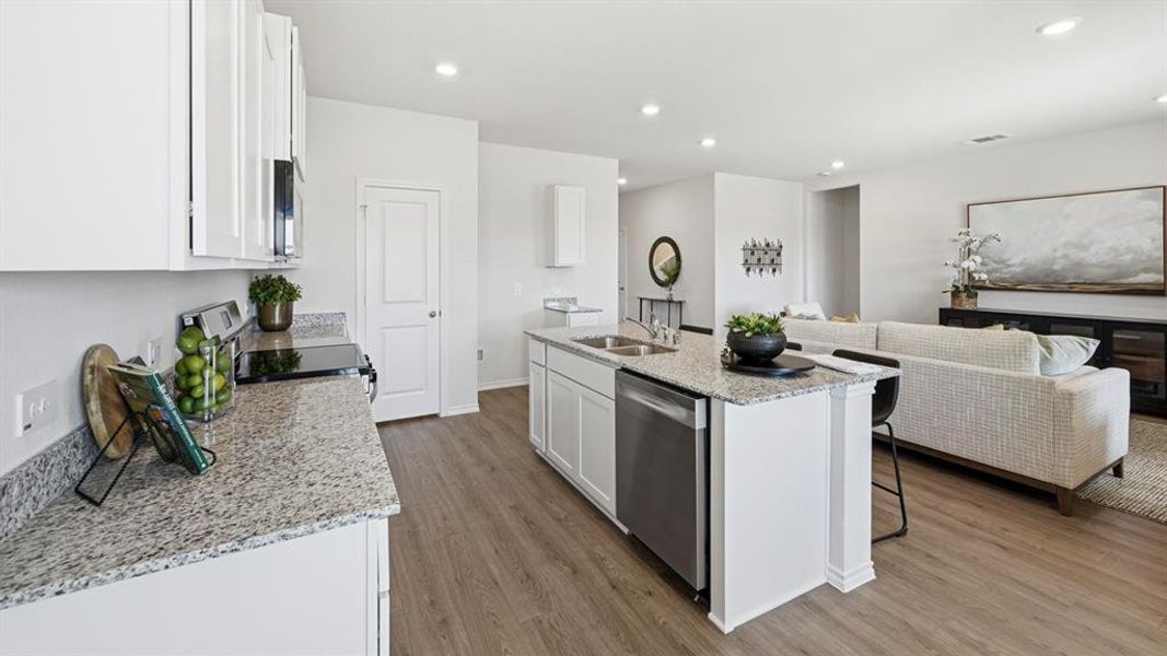 Kitchen with white cabinets, open floor plan, light stone counters, a kitchen island with sink, and black appliances Kitchen with white cabinets, open floor plan, light stone counters, a kitchen island with sink, and black appliances