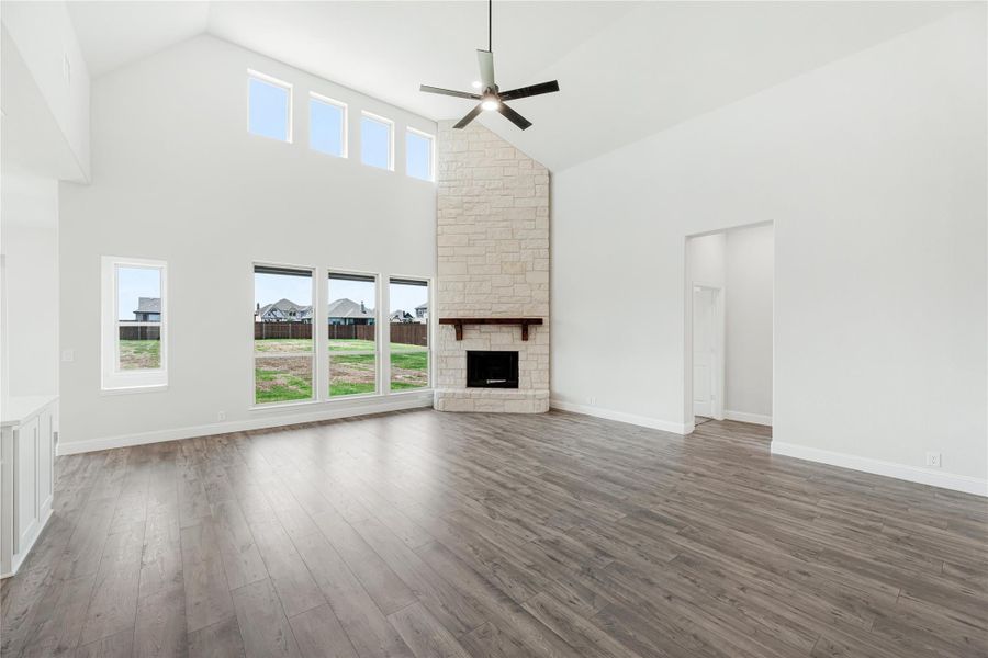 Open living room with vaulted ceiling, floor-to-ceiling stone fireplace, and hardwood floors