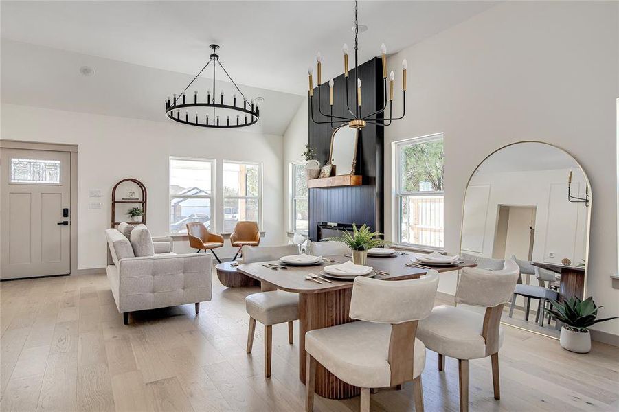 Dining area featuring light wood finished floors, high vaulted ceiling, and a chandelier