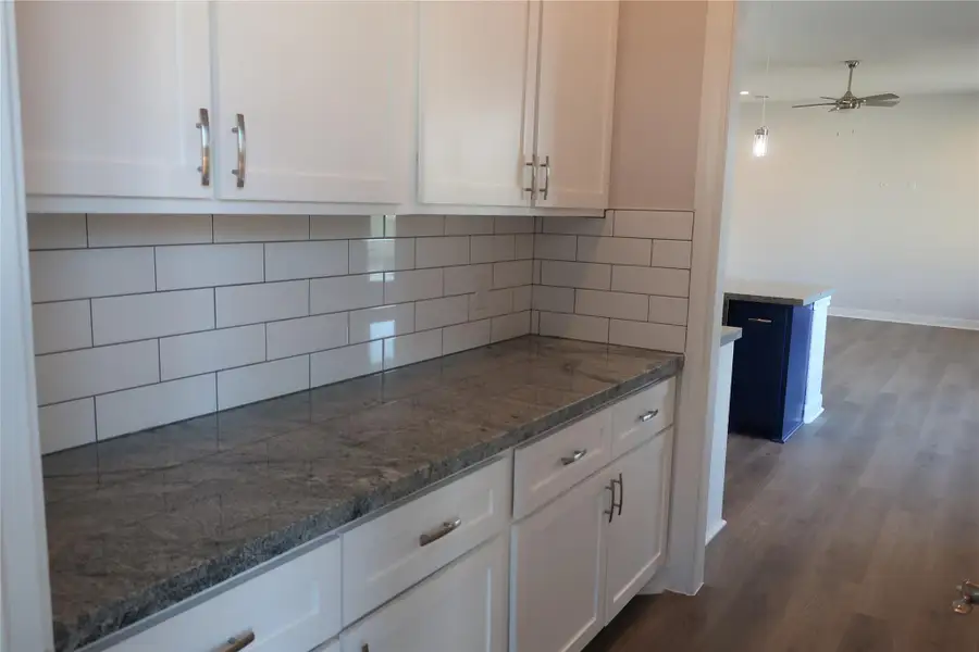 Kitchen with ceiling fan, decorative backsplash, white cabinets, and dark wood-style flooring Kitchen with ceiling fan, decorative backsplash, white cabinets, and dark wood-style flooring