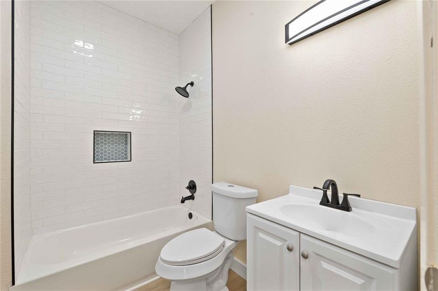 Bathroom featuring vanity, washtub / shower combination, and a textured wall Bathroom featuring vanity, washtub / shower combination, and a textured wall