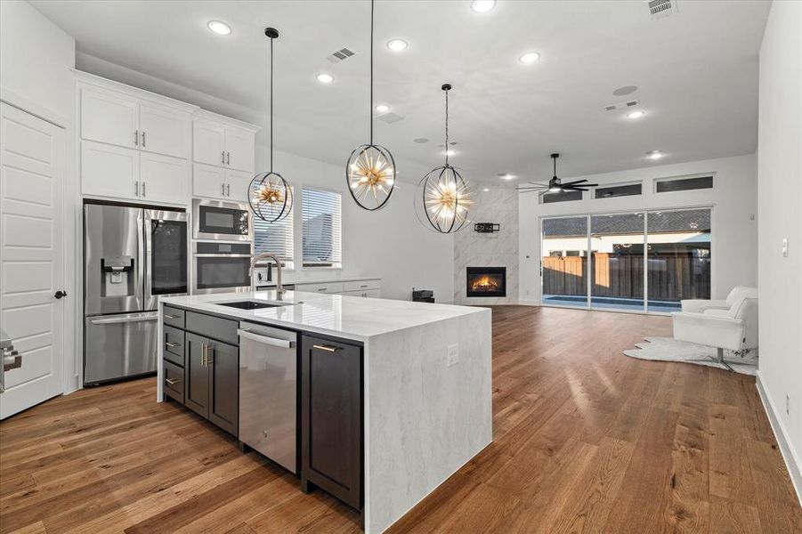 Kitchen featuring recessed lighting, appliances with stainless steel finishes, white cabinetry, light wood-type flooring, and light stone counters Kitchen featuring recessed lighting, appliances with stainless steel finishes, white cabinetry, light wood-type flooring, and light stone counters