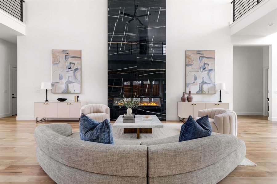 Living room with a high ceiling, wood finished floors, and a fireplace Living room with a high ceiling, wood finished floors, and a fireplace