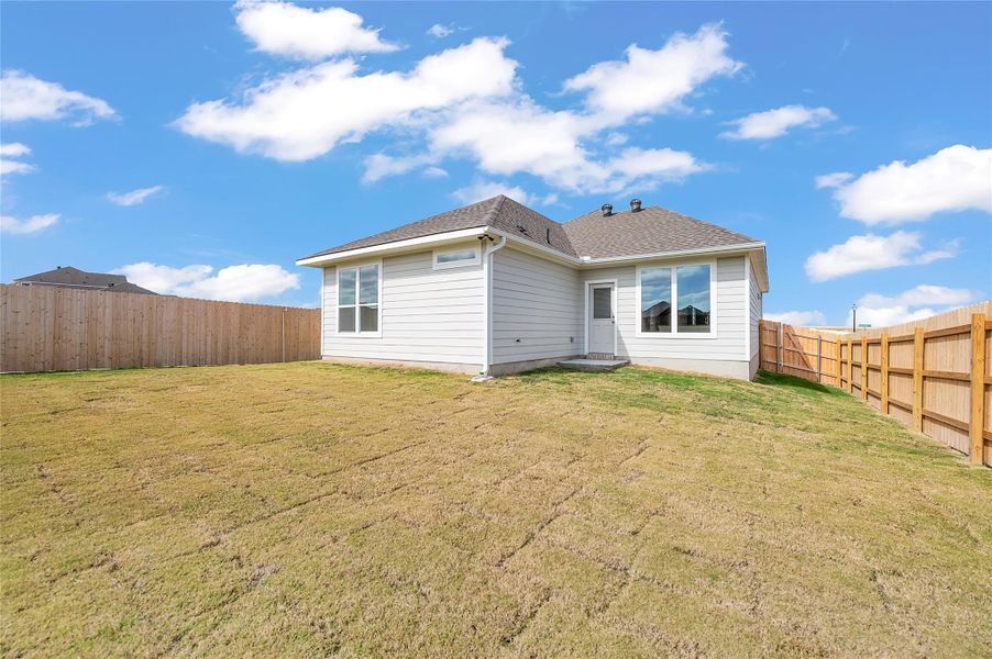 Rear view of property featuring a fenced backyard and a shingled roof