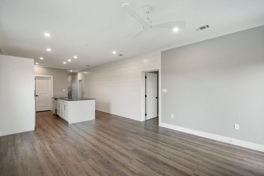 Unfurnished living room with recessed lighting, dark wood-style floors, ceiling fan, and crown molding