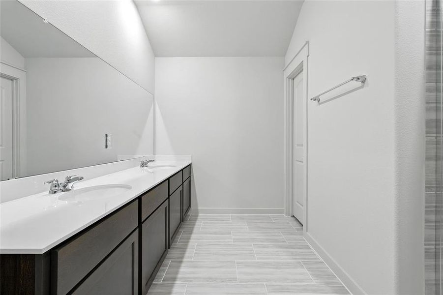 Bathroom featuring double vanity and baseboards Bathroom featuring double vanity and baseboards