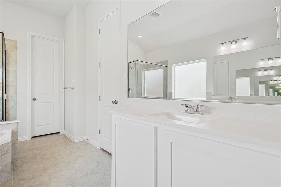 Bathroom featuring vanity, lofted ceiling, plus walk in shower, and tile patterned flooring