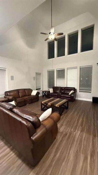 Living area with dark wood finished floors, a ceiling fan, and high vaulted ceiling