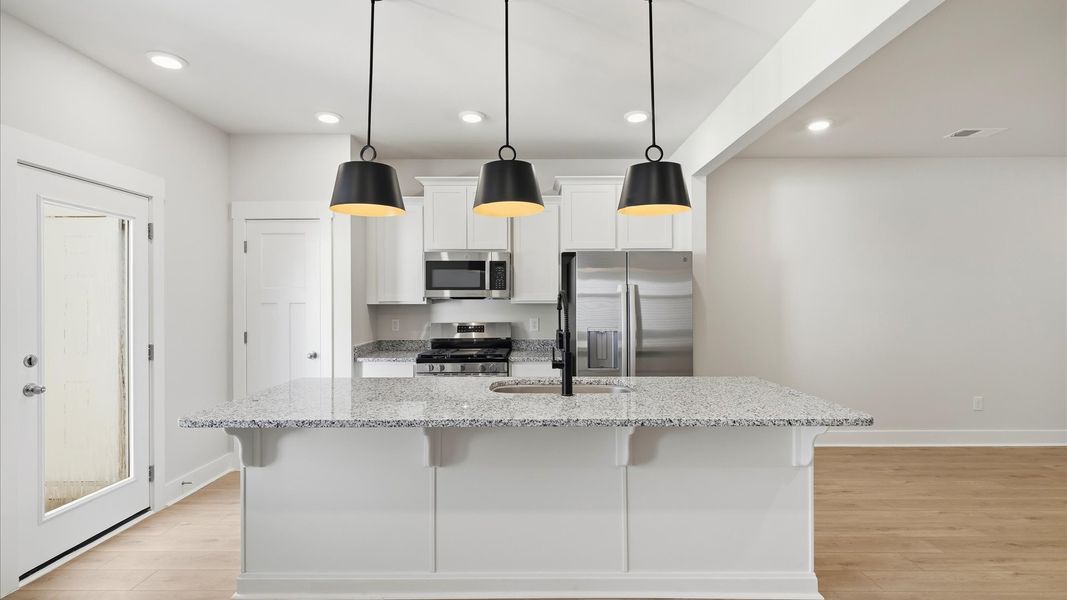 Elegant kitchen with large island and pendant lighting in this first-class DRB Homes design