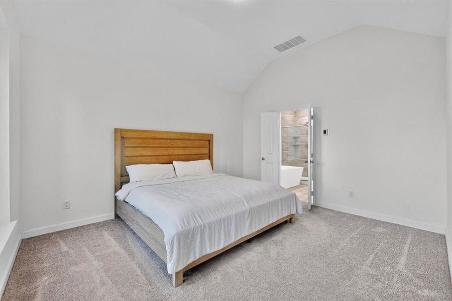 Bedroom featuring carpet, ensuite bathroom, and high vaulted ceiling Bedroom featuring carpet, ensuite bathroom, and high vaulted ceiling
