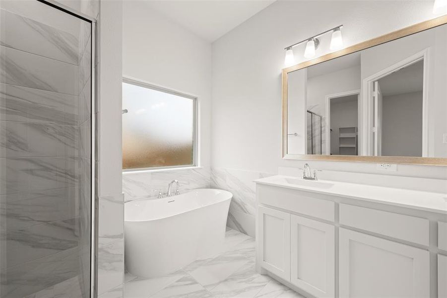 Full bathroom featuring marble look tile flooring, vanity, a freestanding tub, a stall shower, and wainscoting