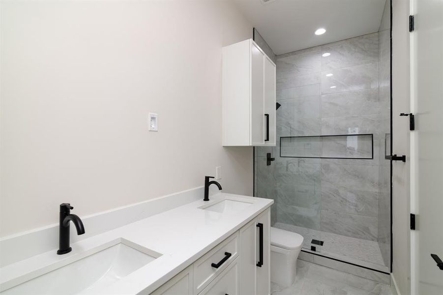 Bathroom with walk in shower, tile flooring, double vanity, and toilet