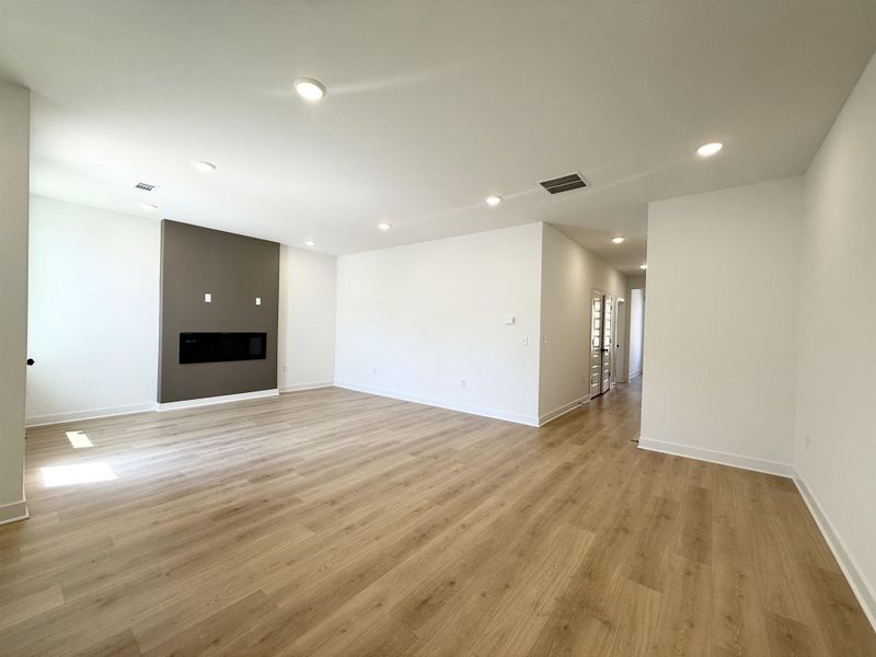 Unfurnished living room with light wood-style flooring, recessed lighting, and a large fireplace