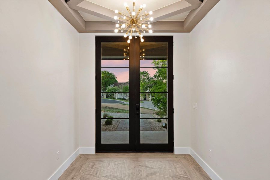 Ornate lighting and a coffered ceiling welcome visitors through these striking glass-paned double doors.