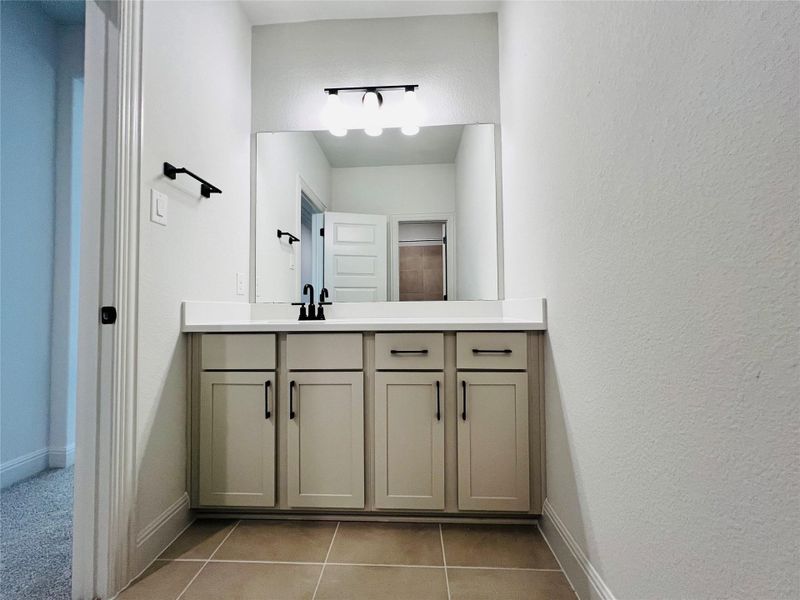 Bathroom featuring vanity, light tile patterned floors, and a textured wall