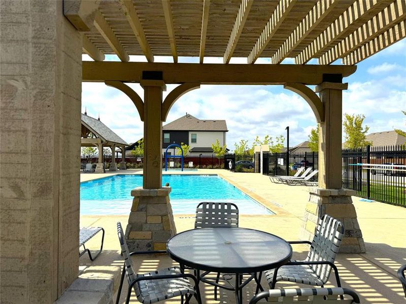 Community pool with a patio area, a pergola, and outdoor dining space