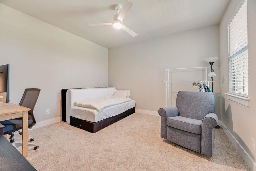 Carpeted bedroom with an office area and a ceiling fan