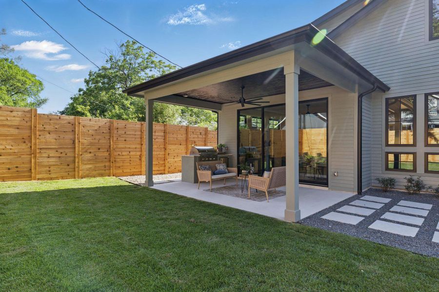 Fenced backyard featuring a ceiling fan and a patio area