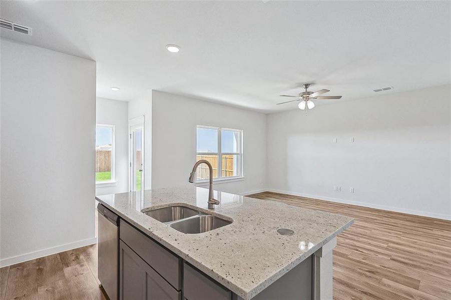 Kitchen with a wealth of natural light, sink, light hardwood / wood-style flooring, and an island with sink