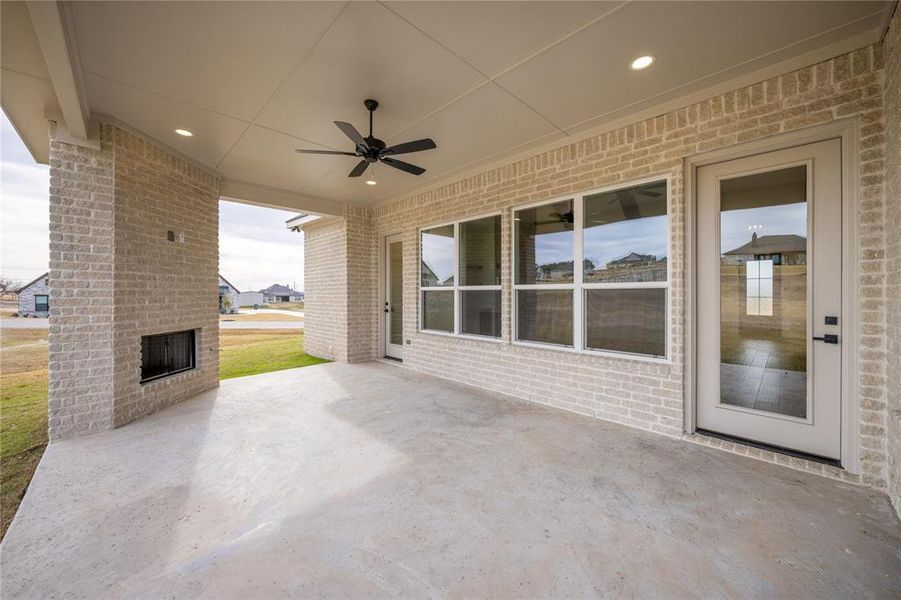 Spacious covered patio featuring a built-in outdoor fireplace, recessed lighting, and a ceiling fan