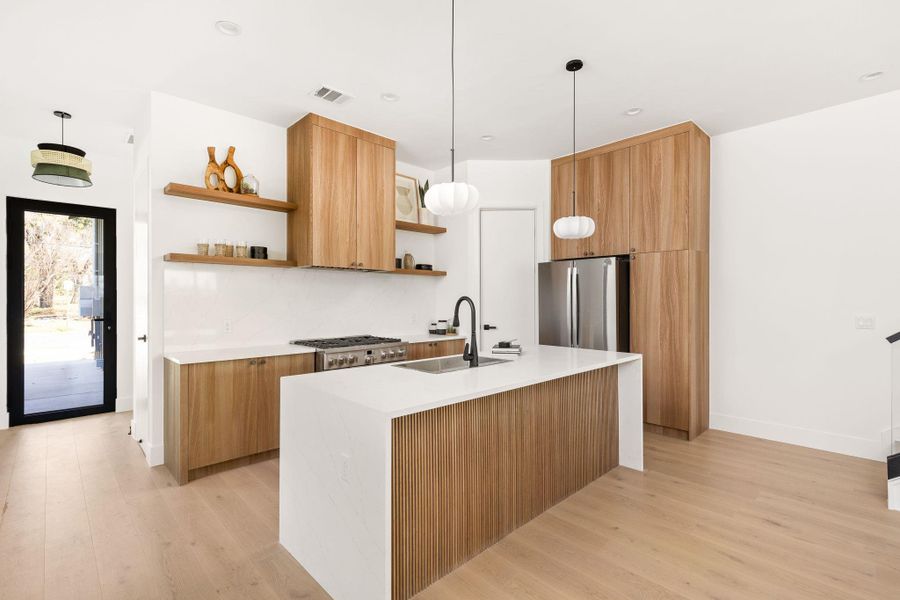 Kitchen with an island with sink, light stone countertops, modern cabinets, and open shelves