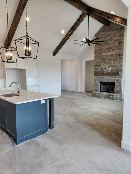 Kitchen featuring beamed ceiling, white cabinets, sink, and decorative light fixtures