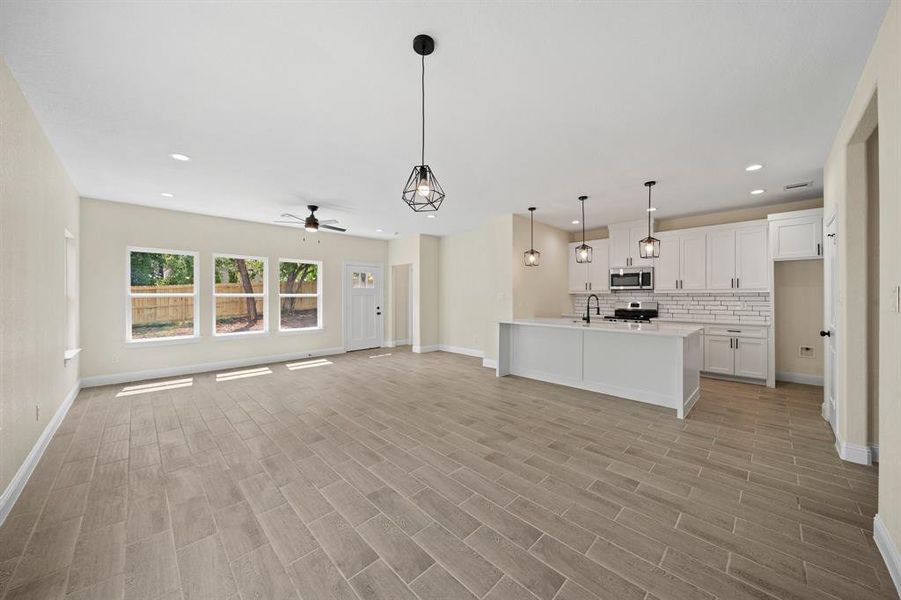 Unfurnished living room featuring sink, ceiling fan, and light hardwood / wood-style floors