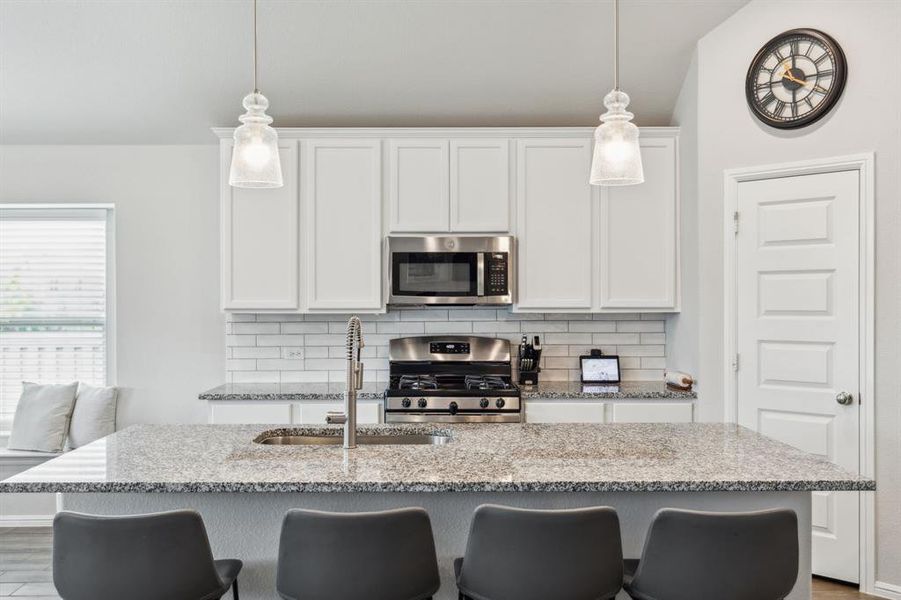 Kitchen featuring island, stainless steel appliances, subway tile backsplash, vaulted ceiling and decorative pendant lighting Kitchen featuring island, stainless steel appliances, subway tile backsplash, vaulted ceiling and decorative pendant lighting