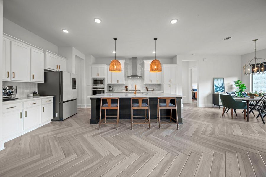 Chef’s kitchen with neutral countertops, oversized island, and stylish pendant lighting. White cabinetry and sleek finishes bring a modern touch. Chef’s kitchen with neutral countertops, oversized island, and stylish pendant lighting. White cabinetry and sleek finishes bring a modern touch.