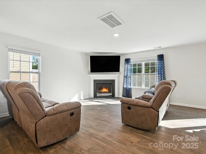 Cozy living space features contemporary gas fireplace as focal point. Abundant natural light from multiple windows and neutral décor create a peaceful retreat with sliding door access to backyard.