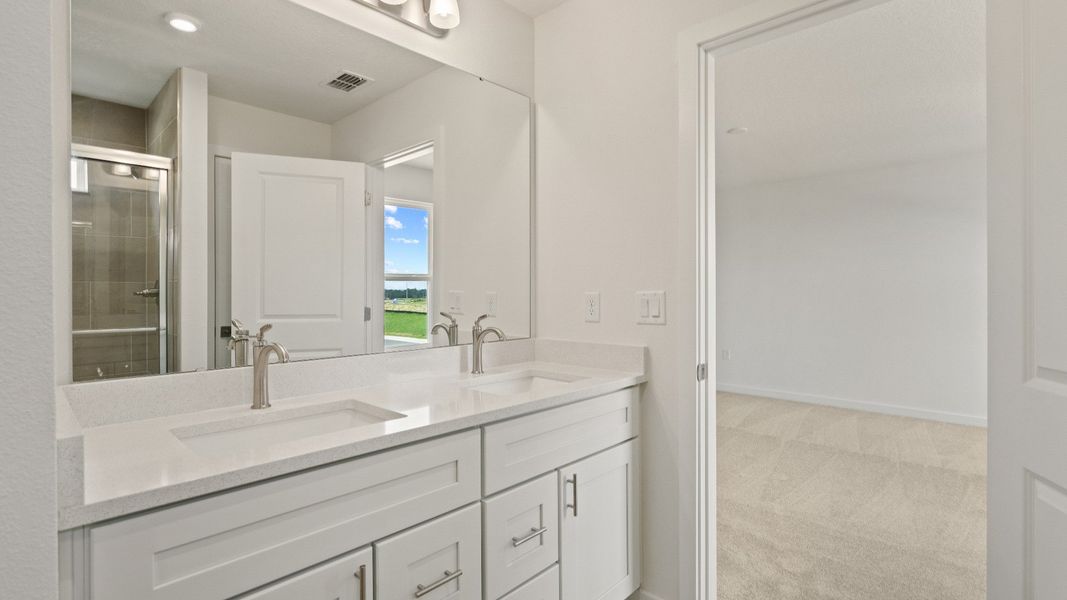 Bright and spacious primary bath with dual sinks, sleek cabinetry, and seamless flow into the adjoining bedroom