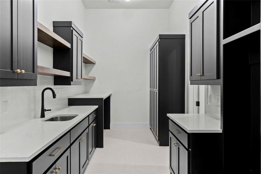 Kitchen featuring open shelves, light stone counters, tasteful backsplash, and dark cabinetry Kitchen featuring open shelves, light stone counters, tasteful backsplash, and dark cabinetry