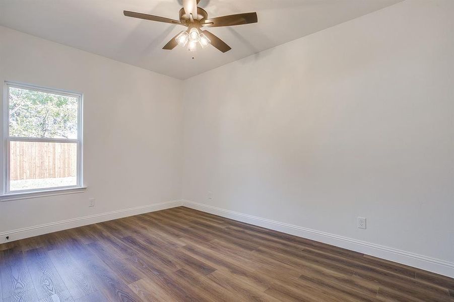 Empty room featuring dark wood-style flooring and a ceiling fan