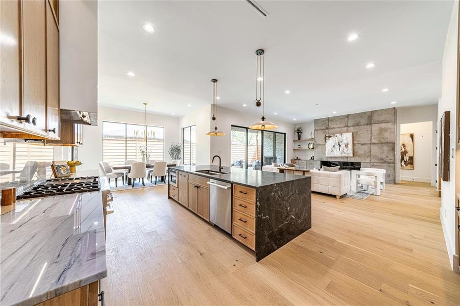 Kitchen with dark stone counters, open floor plan, a large island, decorative light fixtures, and light wood-style floors