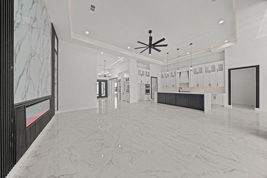 Unfurnished living room featuring light marble finish floors, a ceiling fan, and a chandelier